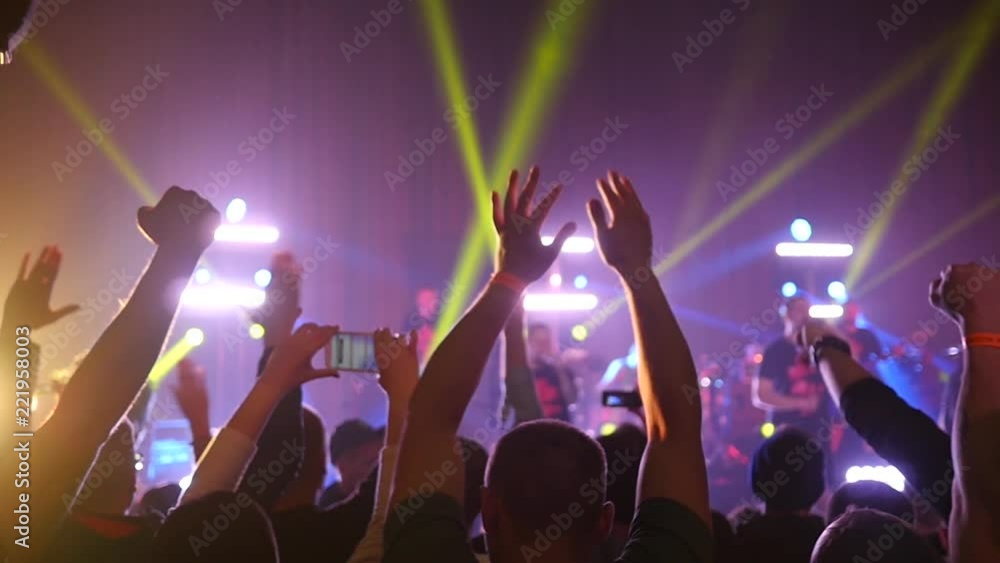Dancing jumping cheering crowd fan spectators rais hands at concert lumiere