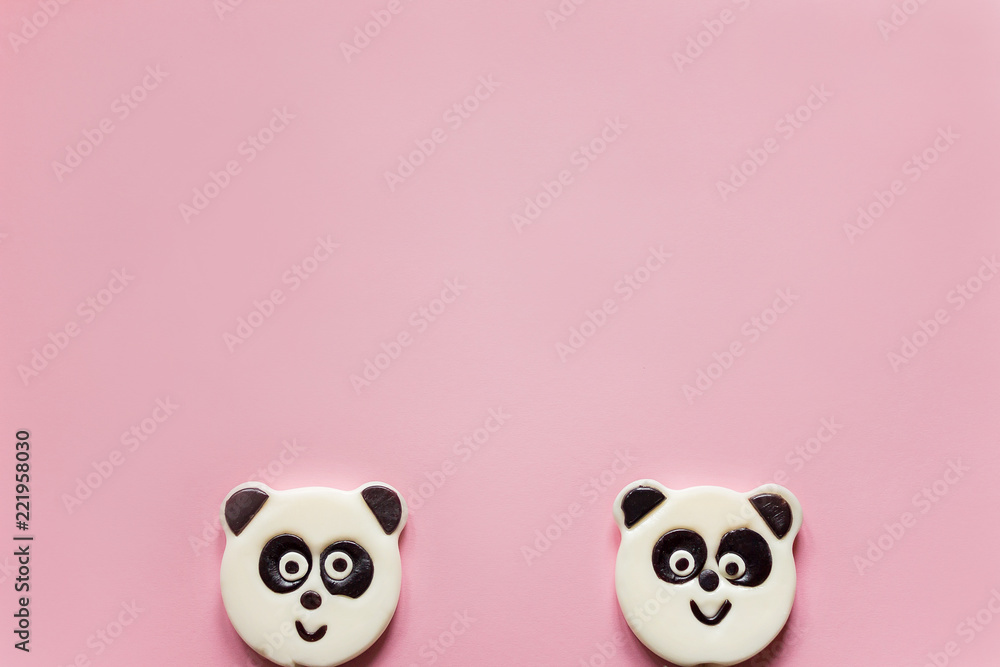 Cute panda lollipops looking out from below a pink background Cute panda lollipops looking out from below a pink background