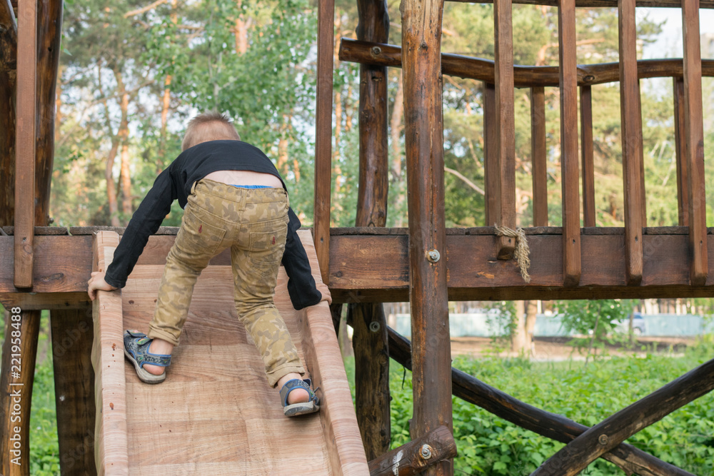 A little boy is climbing a children's hill in the park in the summer. The child is 3-5 years old. Active rest on a children's playground. A little boy is climbing a children's hill in the park in the summer. The child is 3-5 years old. Active rest on a children's playground.