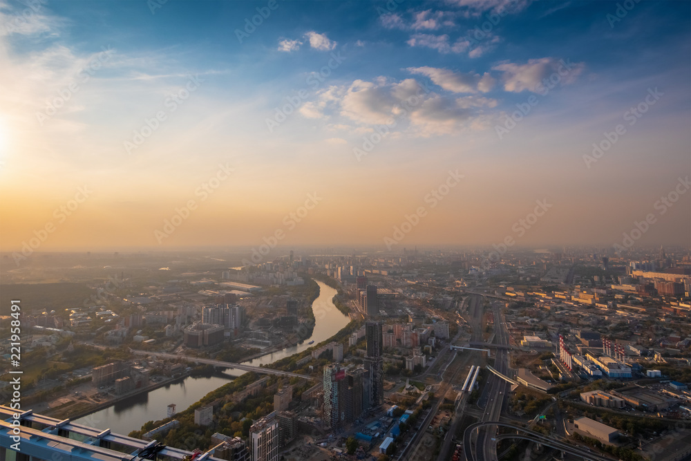 Aerial top view of Moscow city panorama at sunset, river and bridges, roads and buildings in evening myst