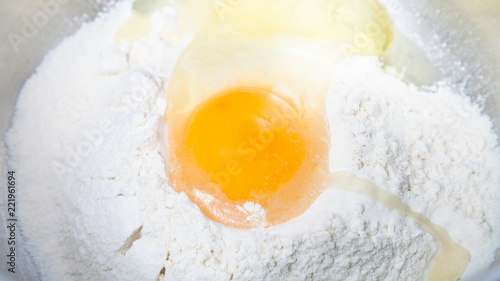 pile of flour with broken egg close up in bowl