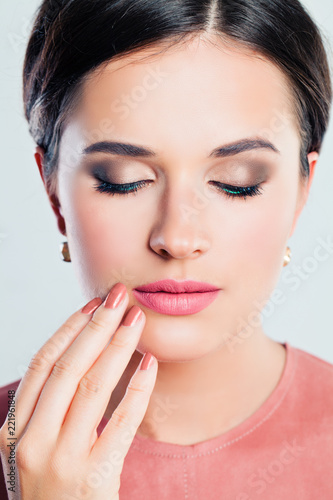Perfect female face closeup. Young woman with makeup and manicured hand. Pink lips and nails