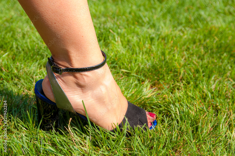 Close-up of a woman's foot with black sandal in the garden.