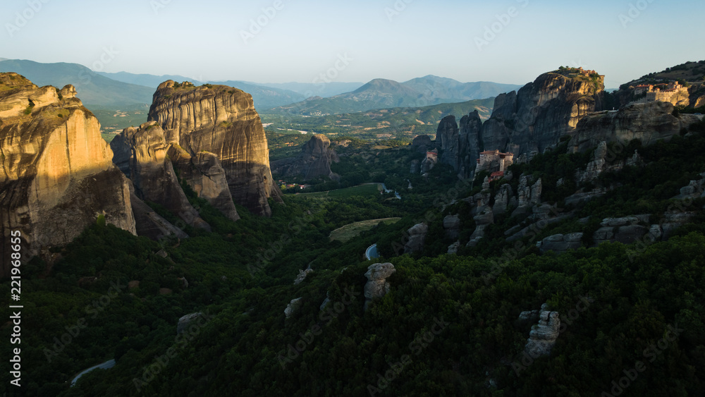 Huge rocks with christian orthodox monasteries at sunrise with Meteora valley in background near Kalambaka, Thessaly, Greece