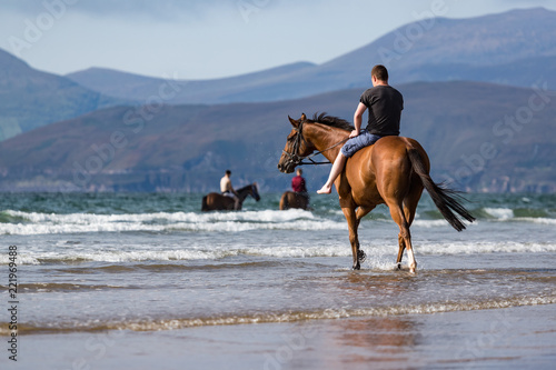 Horse riding on rossbeigh beach in County Kerry, scenic view of the Dingle pinninsula in the distance