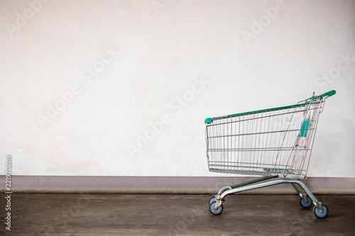 Empty shopping cart on gray wall background .Shopping cart and wall, process vintage tone.copy space for insert text or use for wallpaper and background. © kanpisut