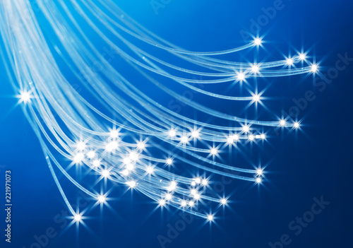 Bundle of optical fibers with lights in the ends. Blue background.