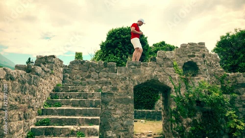 Young man in red tshirt photographing ancient ruined buidings photo