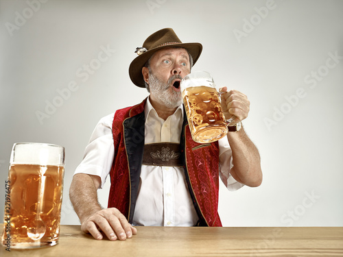 Germany, Bavaria, Upper Bavaria. The senior happy smiling man with beer dressed in traditional Austrian or Bavarian costume with beer at pub or studio. The celebration, oktoberfest, festival concept