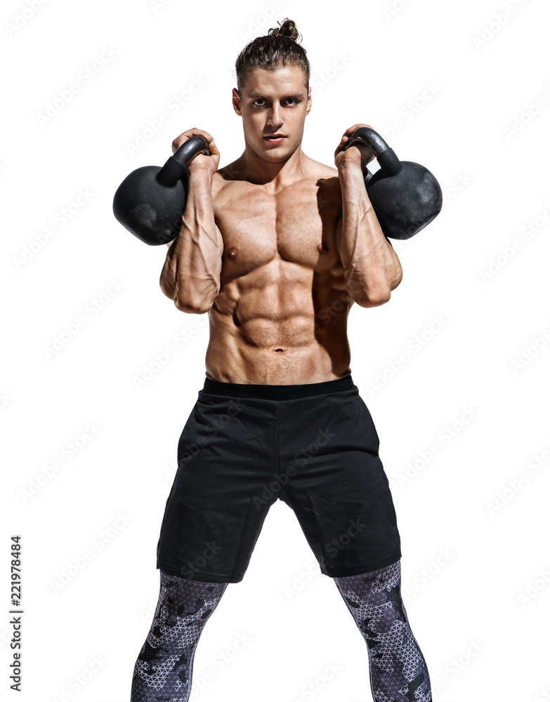 Young muscular guy training with kettlebells. Photo of sporty model with naked torso and good physique on white background. Strength and motivation