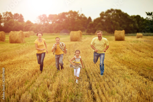 Happy family running on wheat field togrther photo