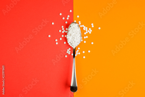 Sugar-replacing tablets spoon on orange and red background photo