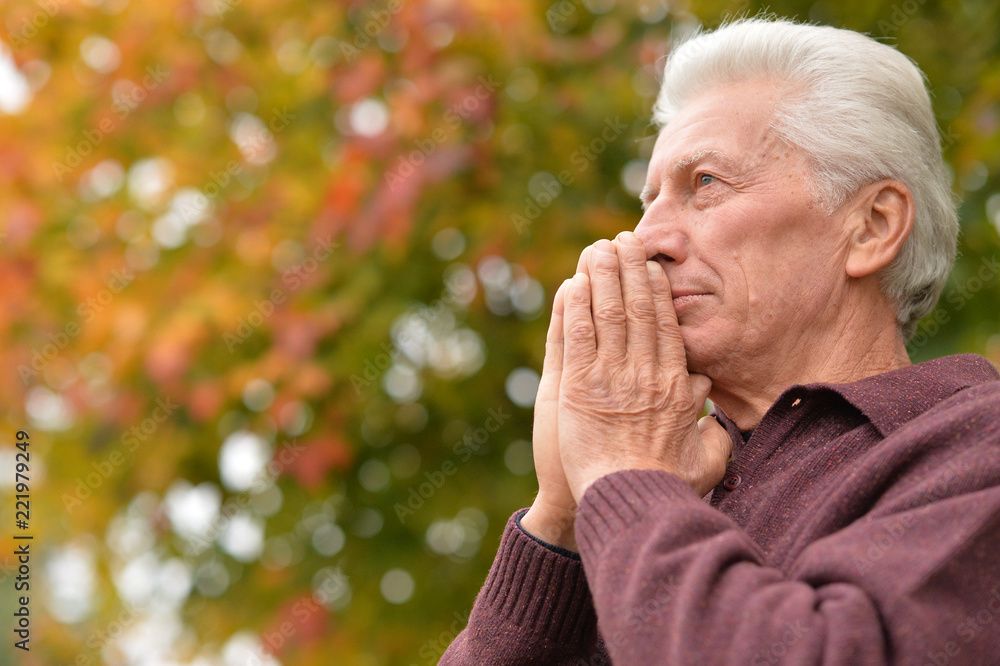 portrait of thoughtful senior man praying in autumn park portrait of thoughtful senior man praying in autumn park