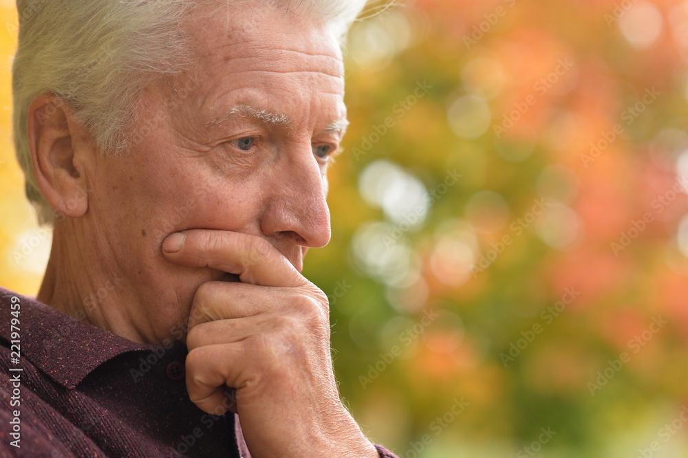 portrait of thoughtful senior man in park portrait of thoughtful senior man in park