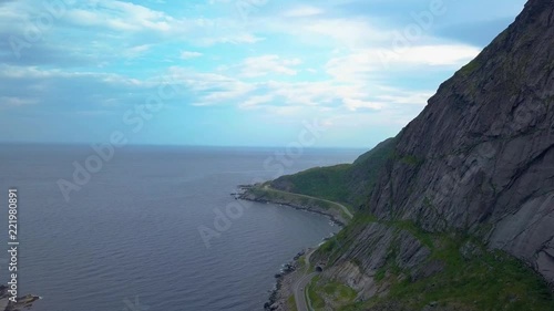 Flight along the mountain over the coast of Norway. Below the road. The Lofoten Islands. 4k photo