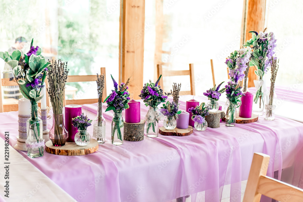 Purple lavender wedding. Table decor with dry lavender, green and white  flowers. Candles, wooden rustic vases, Glass jars, lace bottles, sawed  wood. Stock Photo