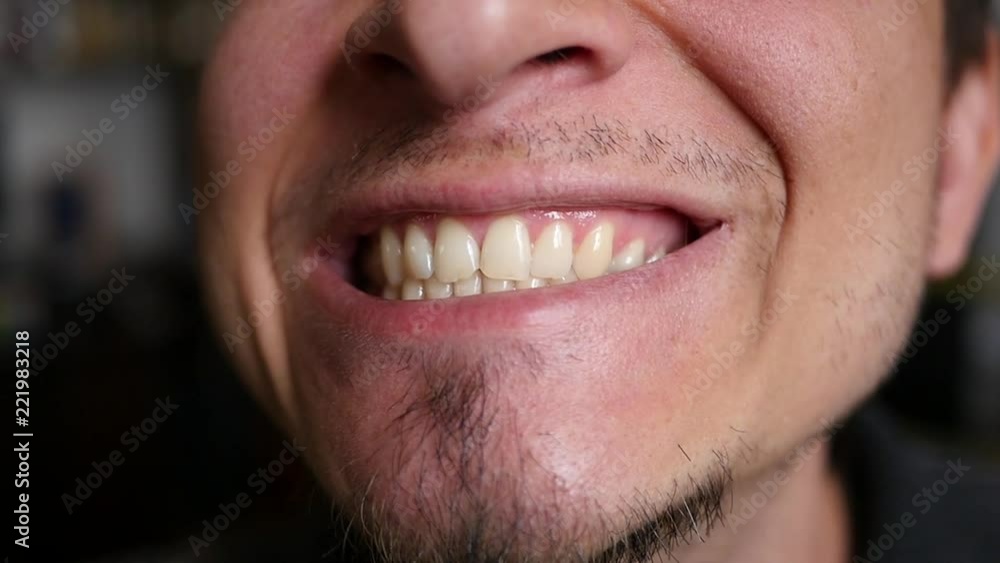 A man looking in the mirror at his teeth and picks them with a fingernail A man looking in the mirror at his teeth and picks them with a fingernail
