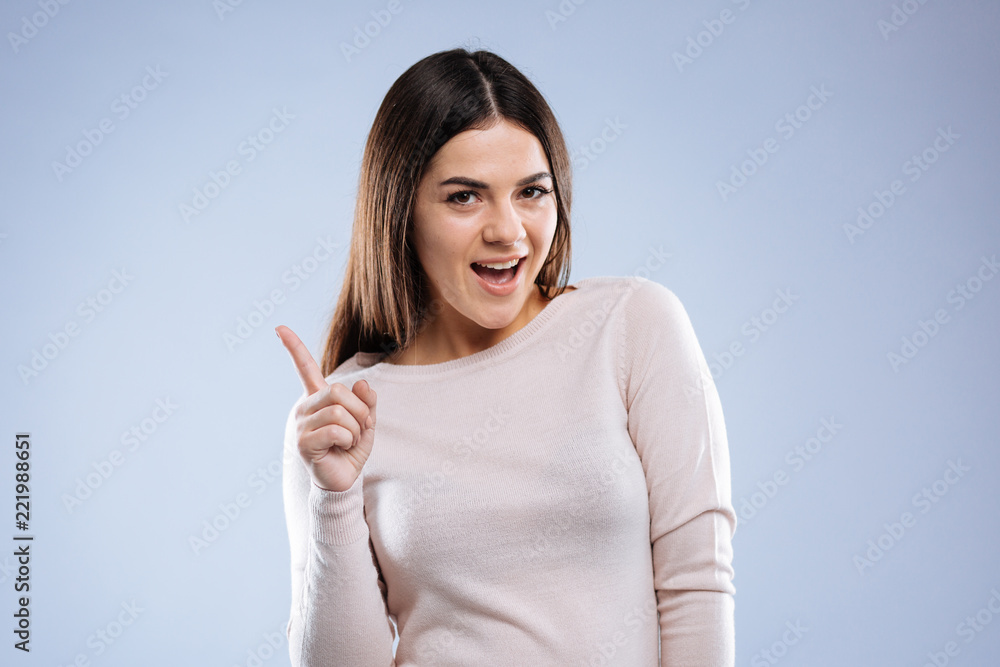 Smart idea. Nice pleasant woman holding her finger up while having a pleasant idea Smart idea. Nice pleasant woman holding her finger up while having a pleasant idea