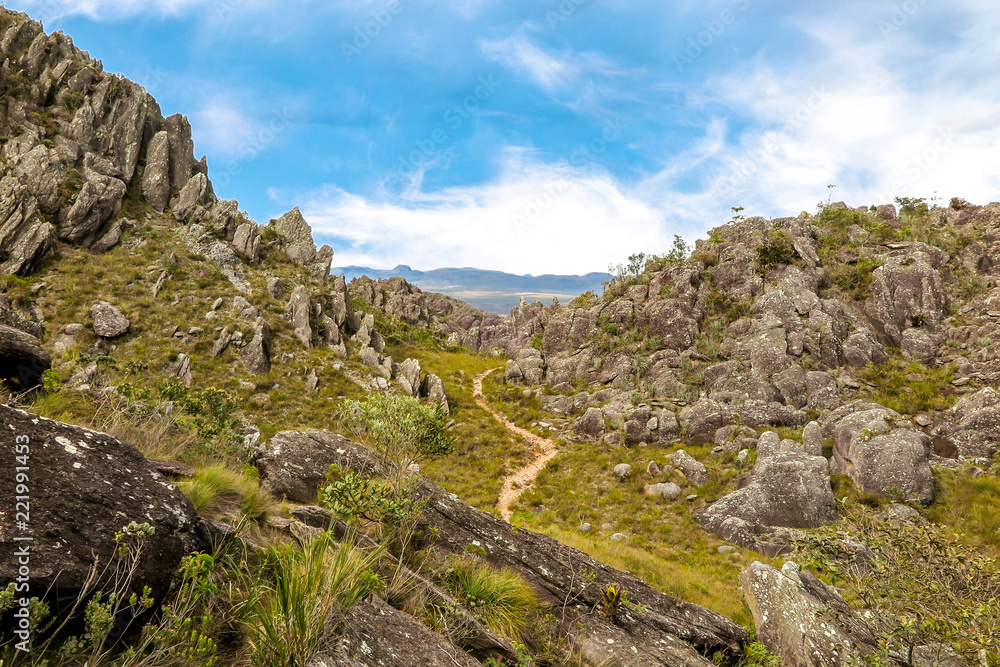 trail in the mountain between rocks with blue sky and clouds, Pico das Almas, Rio de Contas, Bahia, Brazil