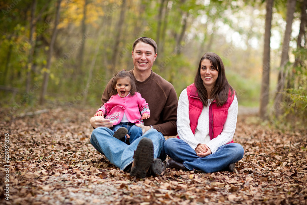 Happy Young Family Sitting in Autumn Woods