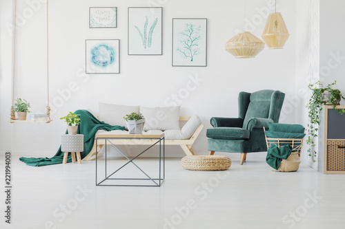 Green accents, graphics and modern coffee table in a living room interior. Real photo