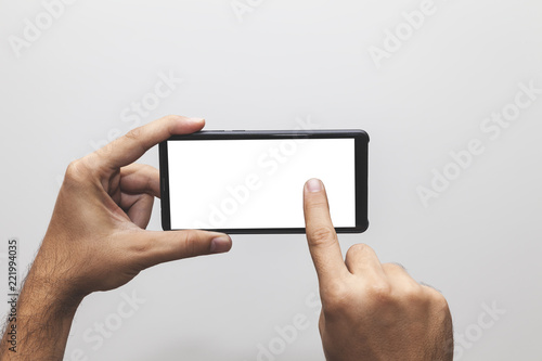 Male hand holding phone with white screen, touching screen, scrolling