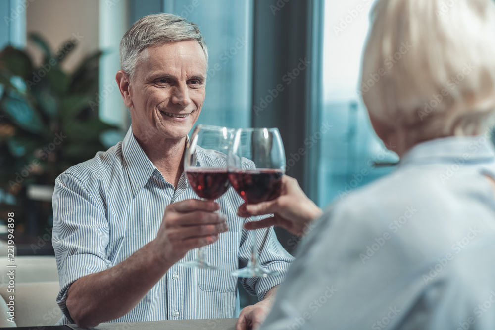 Love you. Handsome male person raising hand while touching glasses with his partner Love you. Handsome male person raising hand while touching glasses with his partner