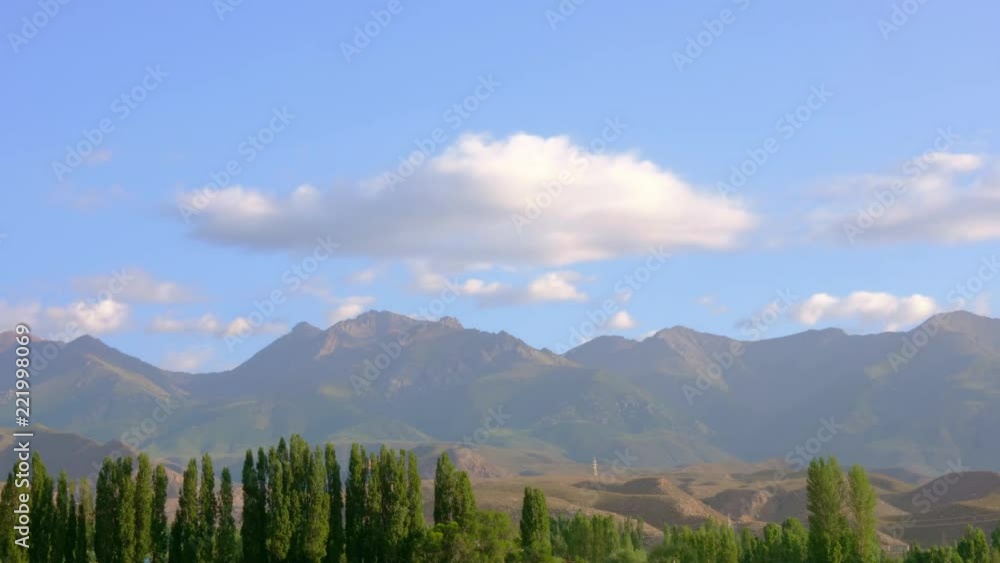 Mountain peaks and green trees on blue sky landscape, timelapse Mountain peaks and green trees on blue sky landscape, timelapse