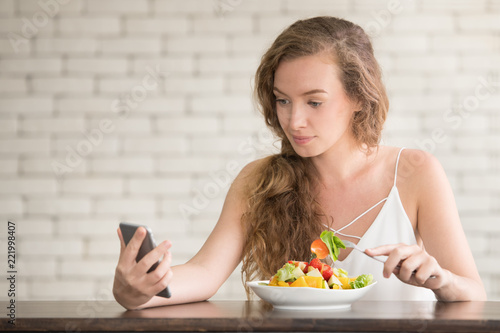 Beautiful young woman in joyful postures with salad bowl on the side photo