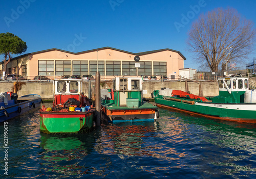 colorful boats loaded with tools moored in front of an industrial warehouse, Venice. Italy