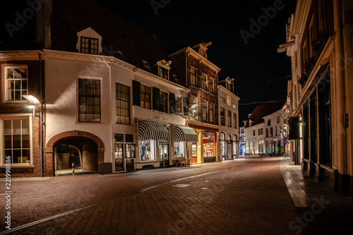 Cozy winding shopping street with illuminated shops in a characteristic medieval town. Monumental medieval houses in Historic old fortified town in the Netherlands  © fotografiecor