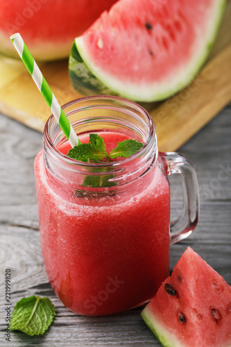 Smoothies cooked from a ripe watermelon in a transparent jar of fruit on a wooden table
