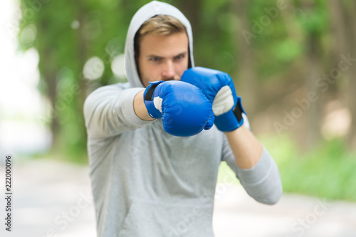 Sportsman concentrated training boxing gloves. Athlete concentrated face sport gloves practice fighting skills nature background. Attack or defend always be ready. Boxer focused on boxing