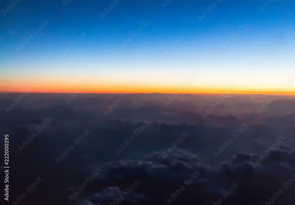 Horizon line of orange sky. Flight over clouds at beautiful golden orange sunset time or light sunrise.