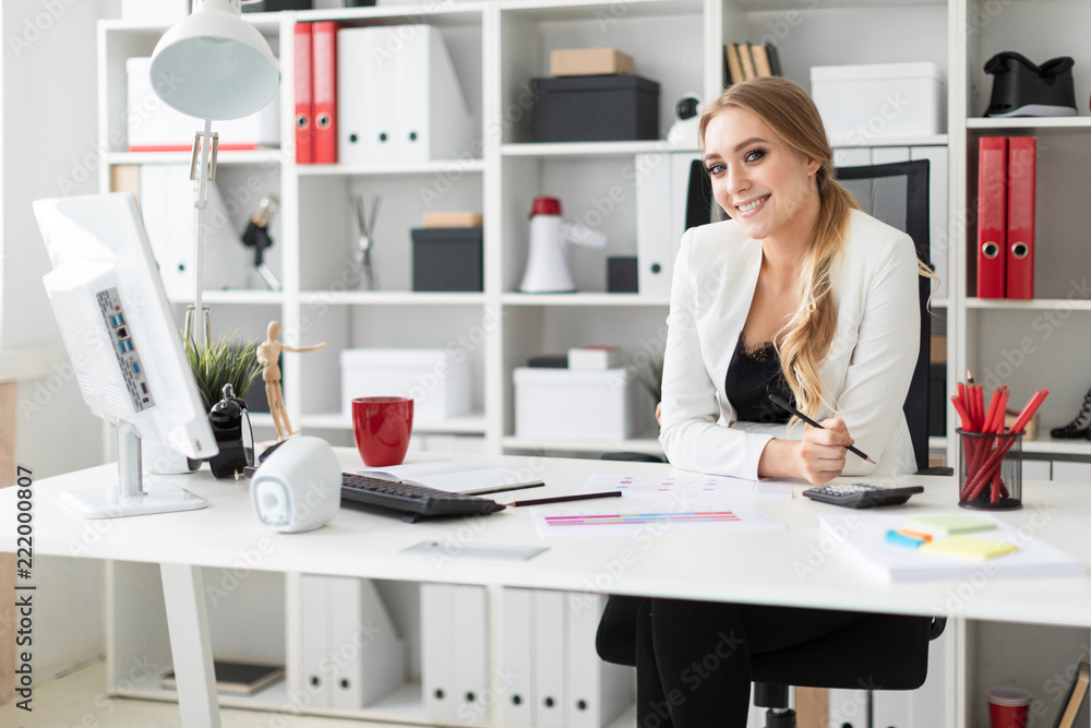A young girl is sitting at the computer desk in the office. A young girl is sitting at the computer desk in the office.