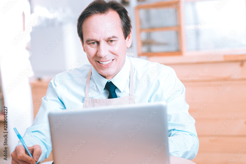 Fototapeta premium Have idea. Pleased businessman keeping smile on his face while and counting incomes