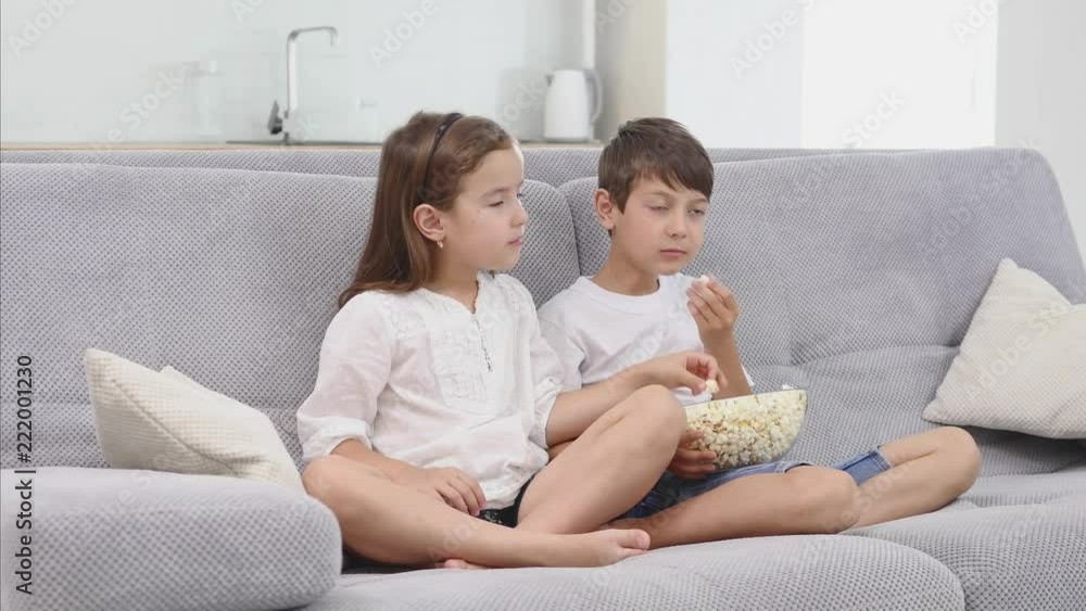 Cute child eat popcorn on sofa and watch tv Cute child eat popcorn on sofa and watch tv