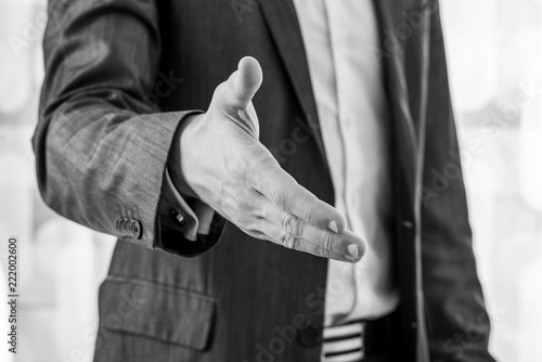 Black and white image of a businessman offering hand in handshake photo