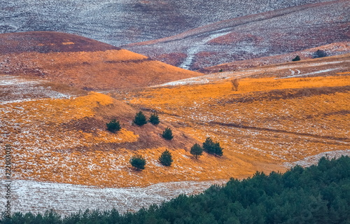 The steppe in the mountains. The winter steppe. Orange, grass with snow. Colorful background.