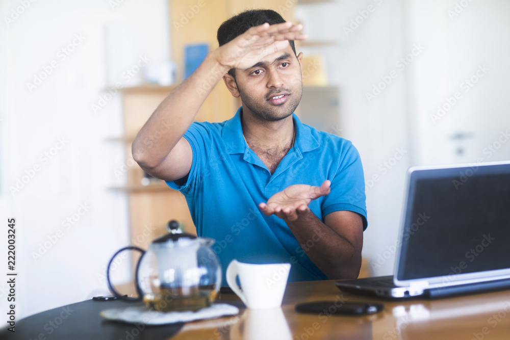 Junger Mann mit Teegefäß arbeitet zu Hause am Schreibtisch Junger Mann mit Teegefäß arbeitet zu Hause am Schreibtisch