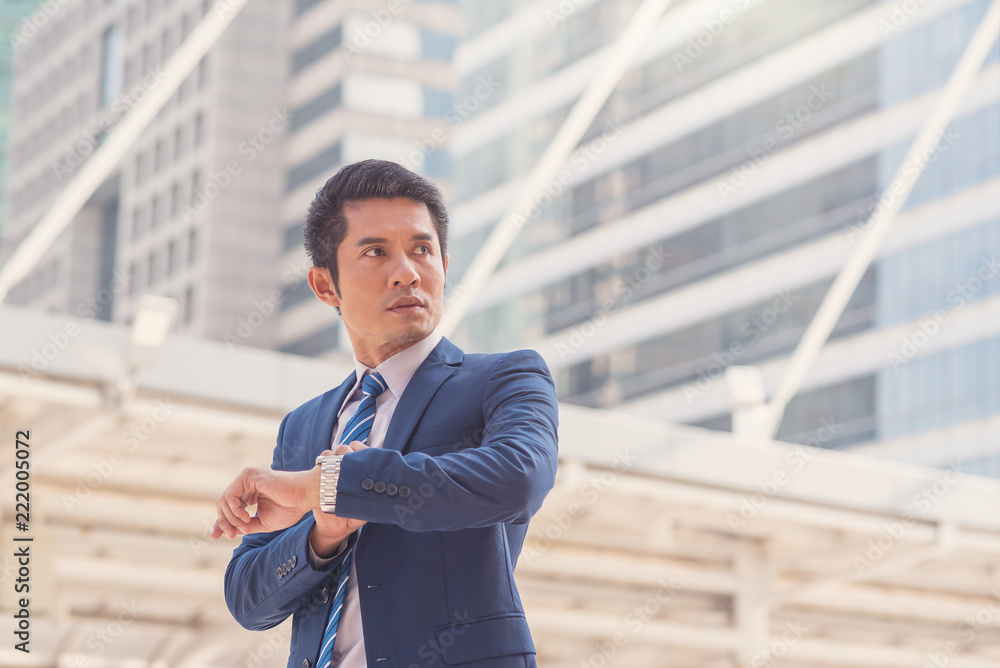 Asian businessmen checking the time on his watch in the city Asian businessmen checking the time on his watch in the city