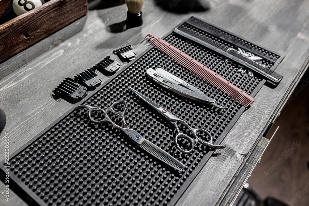 Fototapeta premium The tools of the hairdresser lie on a black mat on the desktop