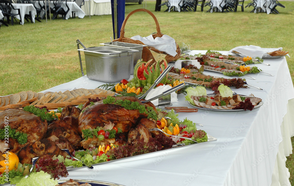 Table in the garden pledged with familiar dishes, sausage, pate, meat