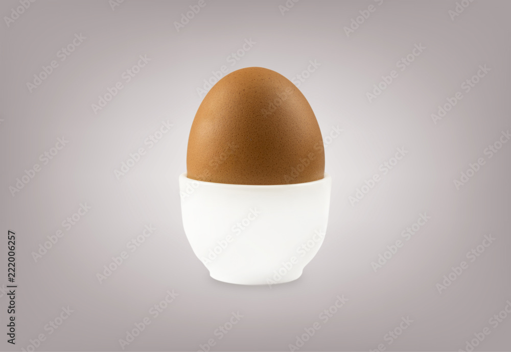 Boiled egg isolated on grey background. Boiled Egg in Eggcup. Close-up of an egg isolated on grey background. Single brown chicken egg.
