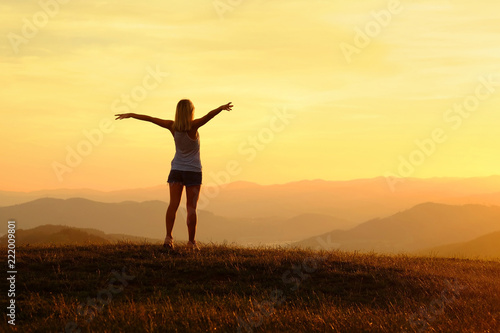 Happy woman with open arms stay on the peak of the mountain top