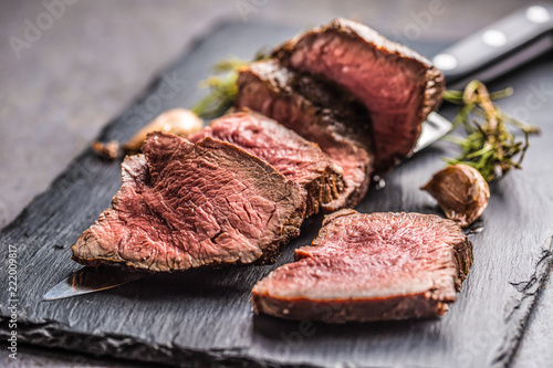 Juicy beef steak with spices and herbs on wooden cutting board