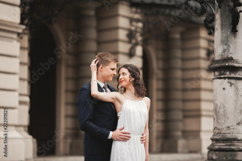 Beautiful wedding couple, bride, groom kissing and hugging against the background of theater © olegparylyak
