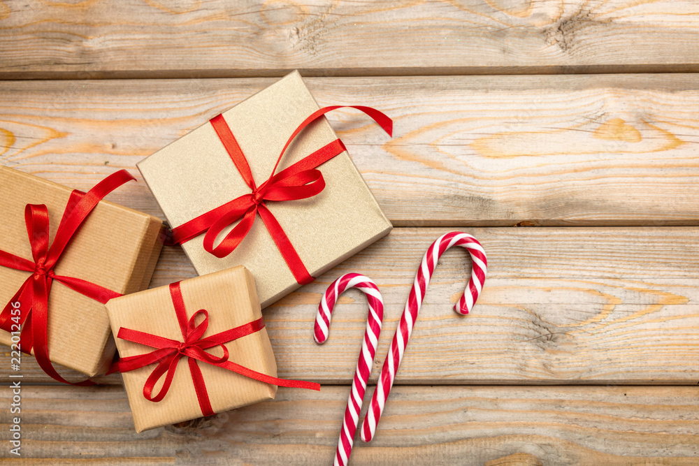 Gift boxes with red ribbon and candy canes on wooden background, copy space, top view Gift boxes with red ribbon and candy canes on wooden background, copy space, top view