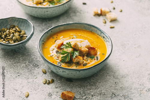 Pumpkin soup in a bowl with croutons and pumpkin seeds. Autumn food.