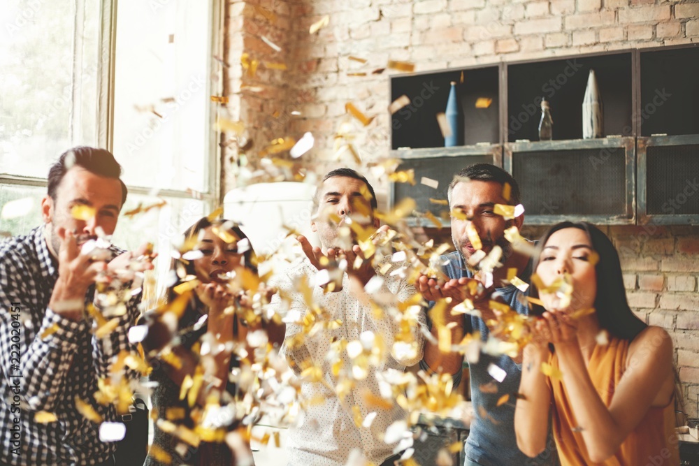 Party fun. Group of beautiful young people throwing colorful confetti and looking happy. - obrazy, fototapety, plakaty 